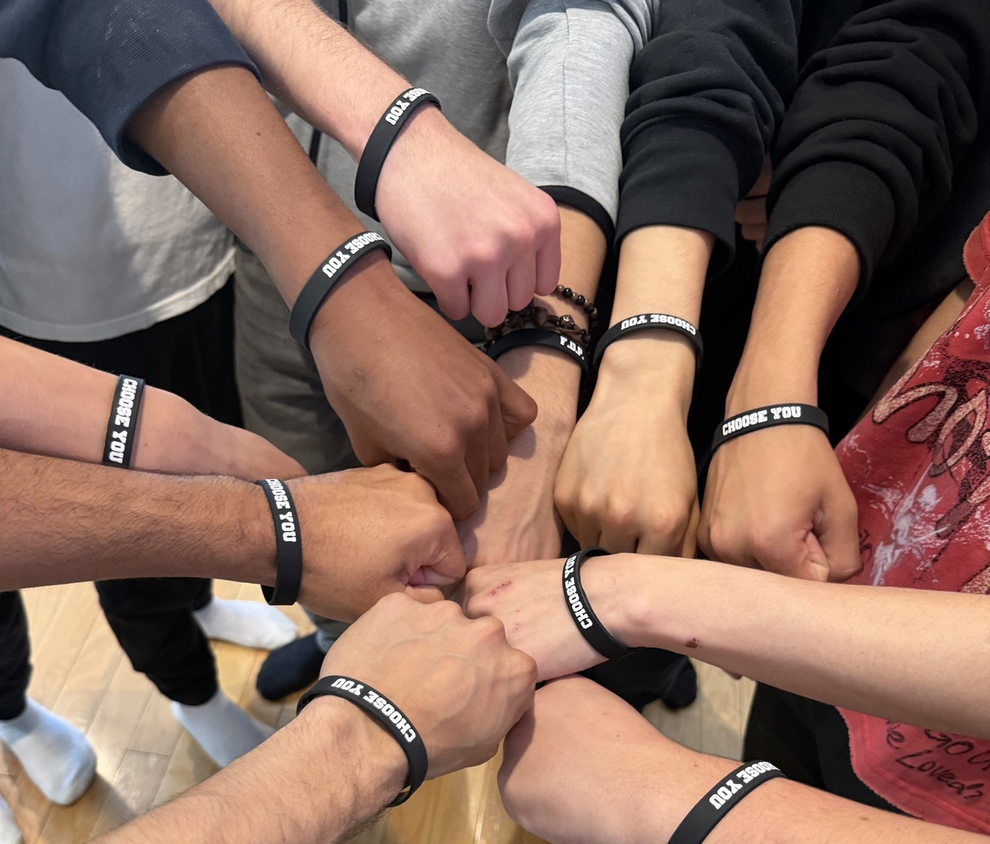 A circle of students' fists, each wearing a Choose You wristband